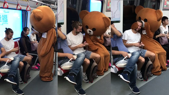 A teddy bear likes the handsome boy on the seat and sits down beside him.