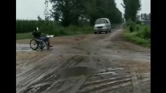  On the dirt road,a van almost ran into a wheelchair.