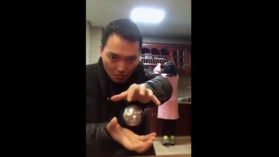 The man was performing a magic trick with metal balls suspended,then his wife came over.