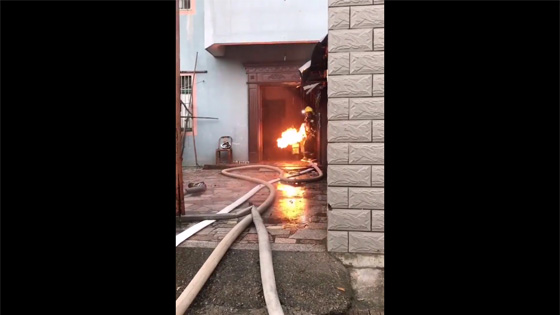 Firemen ran out of a residential building carrying a can of burning gas tank.