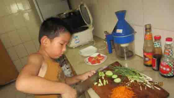 This little child is learning how to cook a meal like his mother!