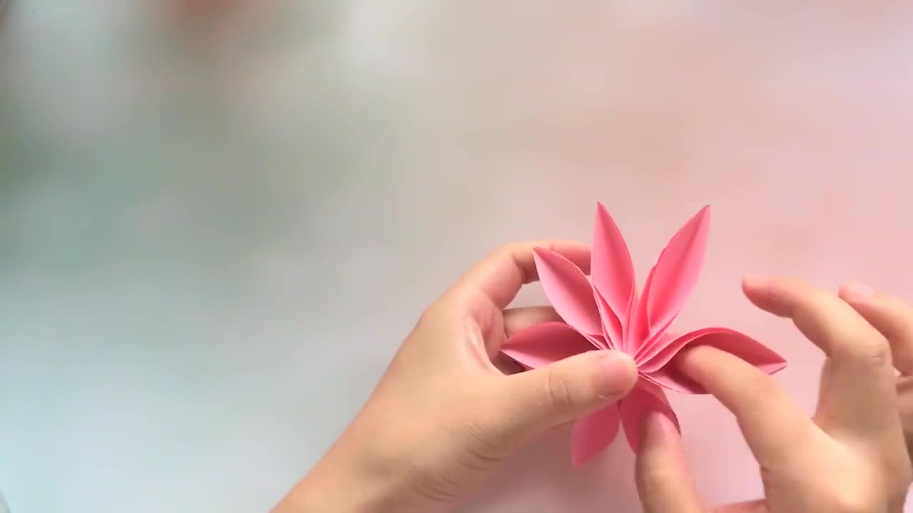 Hands teach you how to fold beautiful eight-petal origami. It's done in a few steps. Hand origami video
