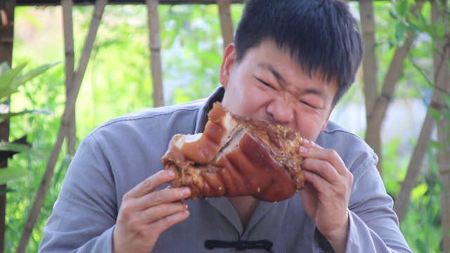 Wild brother eats pig's elbow. He chew and look at it.