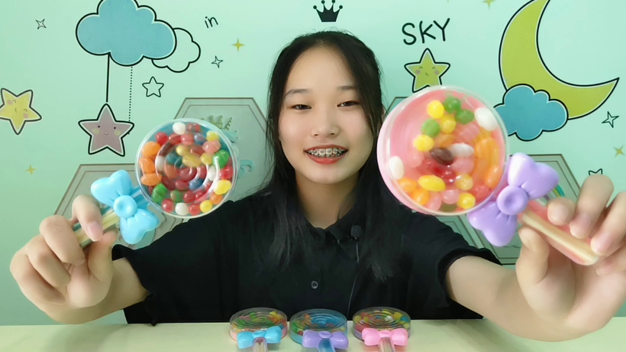 Girls try to eat "colorful candy beans", super lollipops look good and interesting, colourful fruit flavor is sweet.