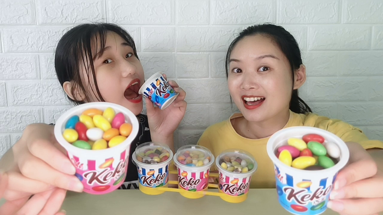 Miss and sister eat interesting chocolate beans, with ice cream cups, colorful and delicious
