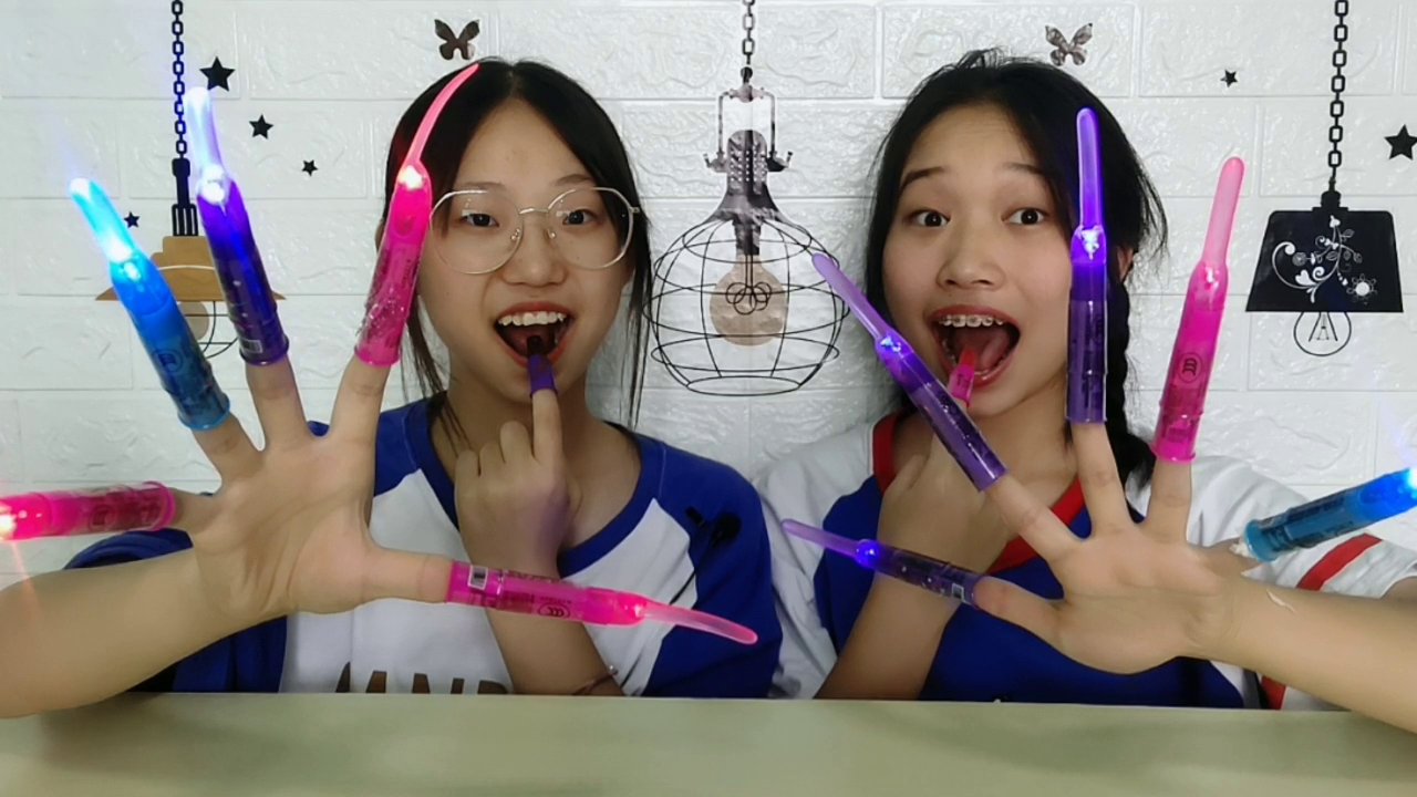 Two girls make shiny nails, wear "electro-optic finger candy" and eat sweets as monsters.