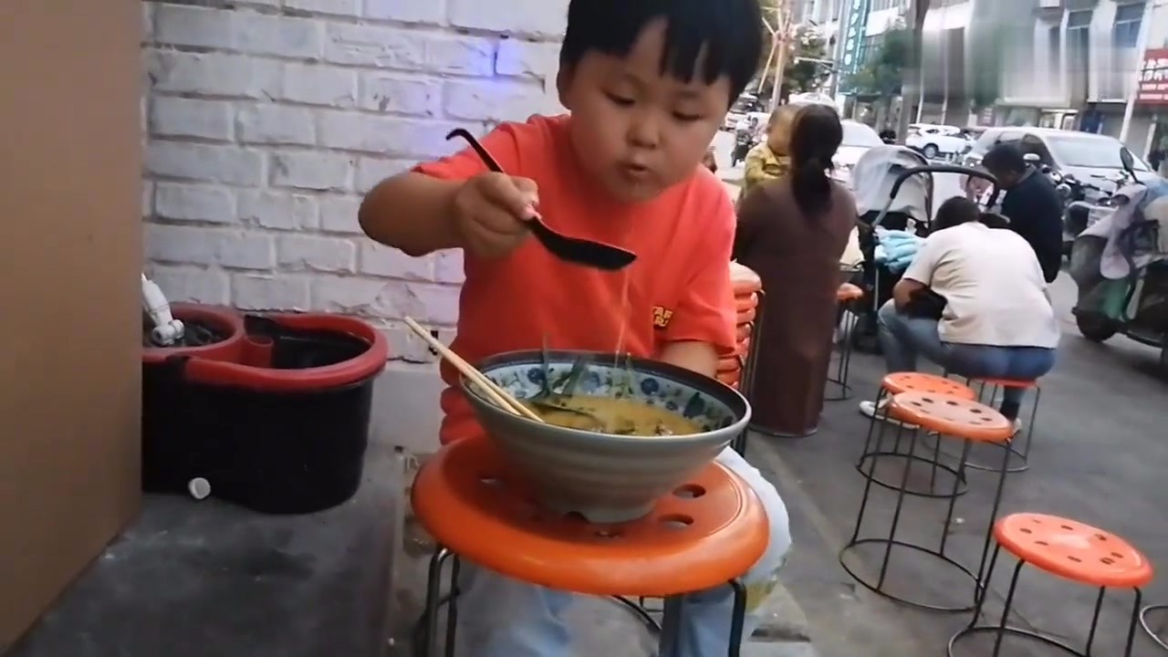Four-year-old children eat hot and spicy food, spoon in left hand and chopsticks in right hand. They are so delicious that they can't stop eating.