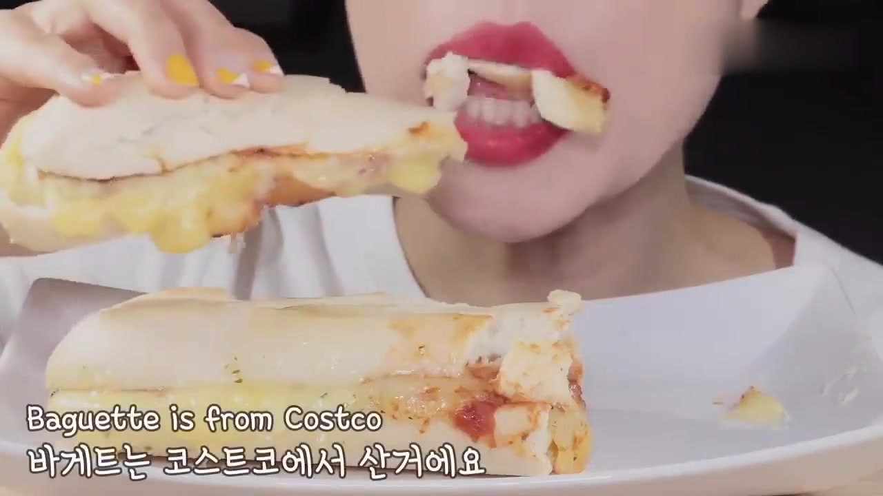 Beauty eats a hamburger with extra cheese. The sandwich overflows when she eats it. It's crisp and sweet.